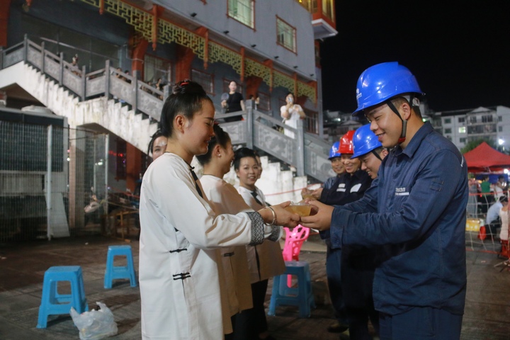 榕江县口寨村啦啦队队员为南方电网贵州凯里榕江供电局在“村超”现场值守保供电工作人员送上冰粉。胡乾摄